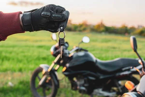 Motosikletlerin arka planında siyah bir ulaşım anahtarı tutan adam.