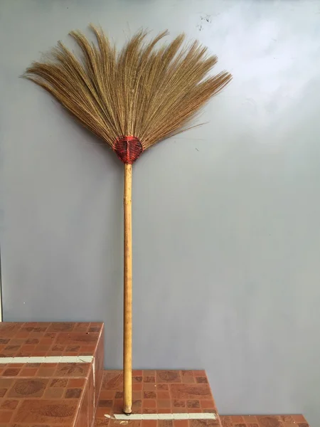 Broom leaning on the gray wall — Stock Photo, Image