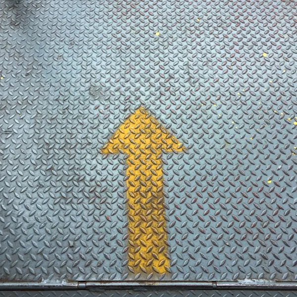 Yellow arow on old metal floor — Stock Photo, Image