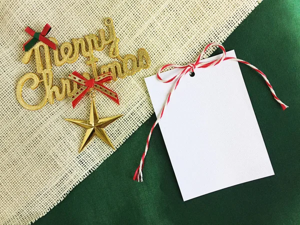 White card paper and merry christmas text on sackcloth - green f — Stock Photo, Image