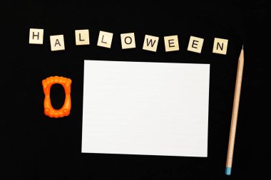 Ahşap, Drakula dişleri plastik oyuncak, kalem ve beyaz kağıt ve tasarımınızı siyah kumaş üzerine alan üzerinde Halloween metin.