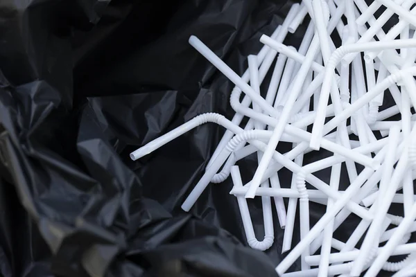 Weiße gebrauchte Strohhalme in einem schwarzen Müllsack — Stockfoto