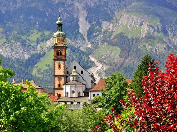 Igreja com torre sineira, folhas coloridas e montanhas — Fotografia de Stock