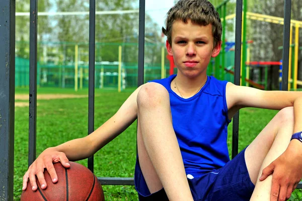 Portret van een kleine basketbalspeler zitten op de rechtbank — Stockfoto