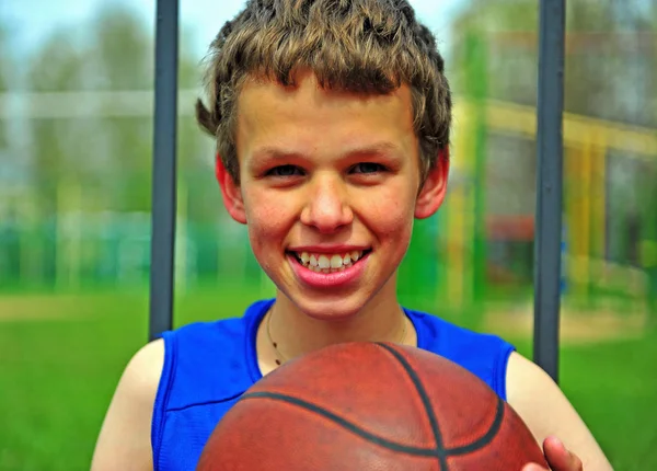 Porträtt av en leende pojke med en basketboll — Stockfoto