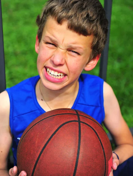 Хлопчик з баскетболом сидить на дворі — стокове фото