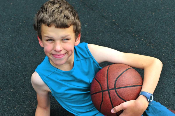 Улыбающийся подросток с баскетбольным мячом — стоковое фото