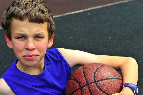 Adolescente sentado na quadra de basquete — Fotografia de Stock