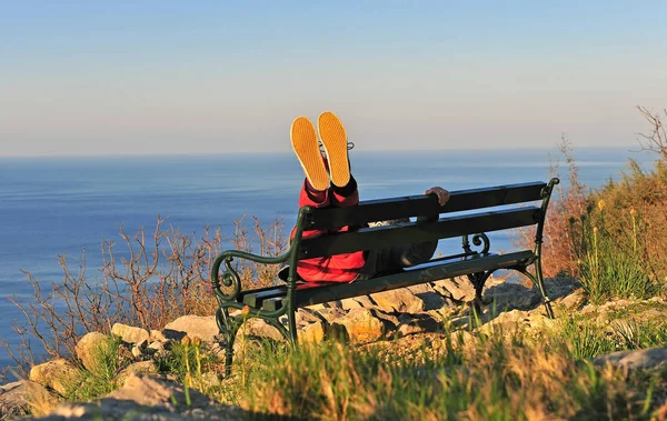 Feet in the air, man lying on the bench