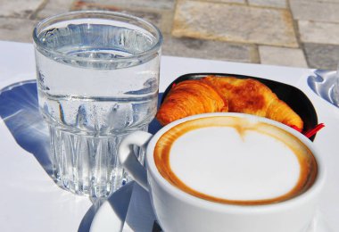 İki bardak kahve kruvasan ve su ile