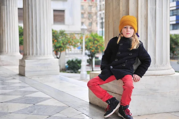 Allvarlig pojke med långt hår som sitter på kolumner — Stockfoto