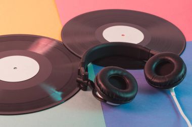 Kulaklıklar ve vinil kayıtlar retro tarzı. Mavi ve kırmızı ışık renkli kağıt üzerinde müzik şeyler.