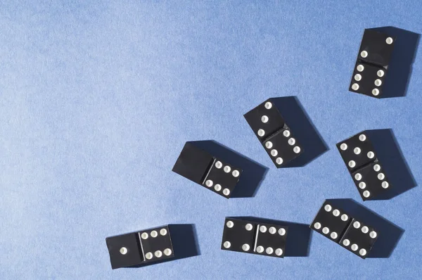 Mavi bir arka plan üzerinde siyah domino. Kavram risk, oyun bağımlılığı ve başarı.