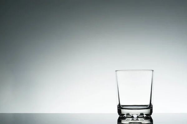 Empty glass on the right of the frame and a blank space on the left on a light background.