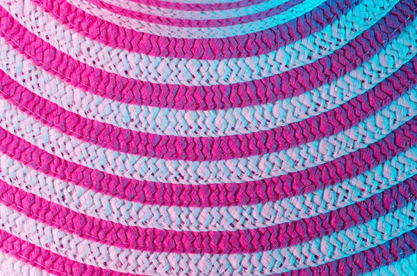 Kırmızı ve beyaz çizgili mor ve turkuaz ışık arka plan. Soğuk ve sıcak tonlarda kumaş dokusuna. Yukarıdan bir görünümü temel bir parçası bir yaz şapka.