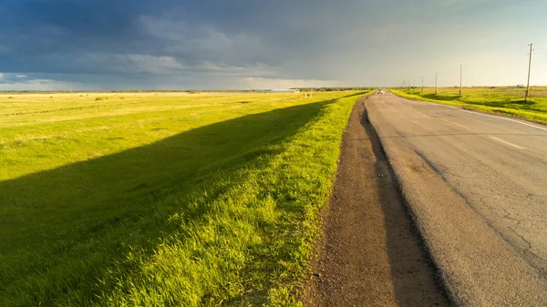 Yağmur sonra gökyüzüne karşı alanın ortasında bir ülke yolda araba mı.