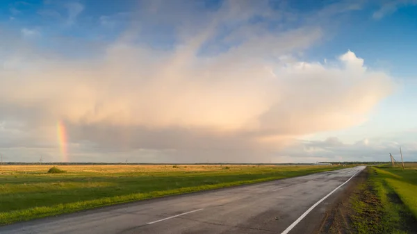 Yağmurdan sonra manzara, bir gökkuşağı gökyüzü karşı alanları arasındaki yol.