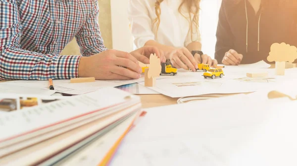 Gençler iş oyun bir biçimde tartışın. Mimarlar bir ev inşa iş modeli. İşadamları planları ve kağıtları ortasında bir masada.  