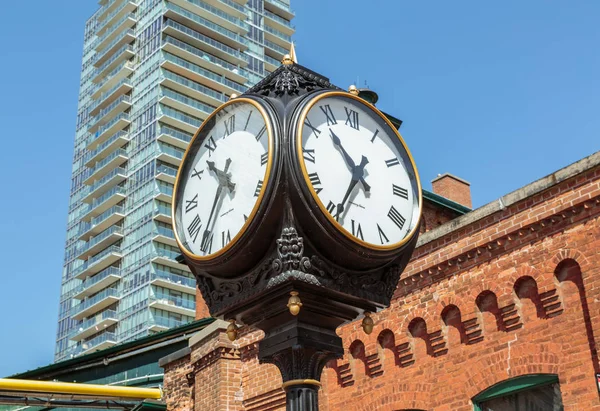 Vintage classic clocks standing against brick  and modern stylish condo building — Stock Photo, Image