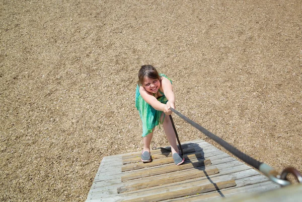 Niña con expresiones faciales divertidas jugando, subiendo en una escalera de madera en el parque al aire libre —  Fotos de Stock