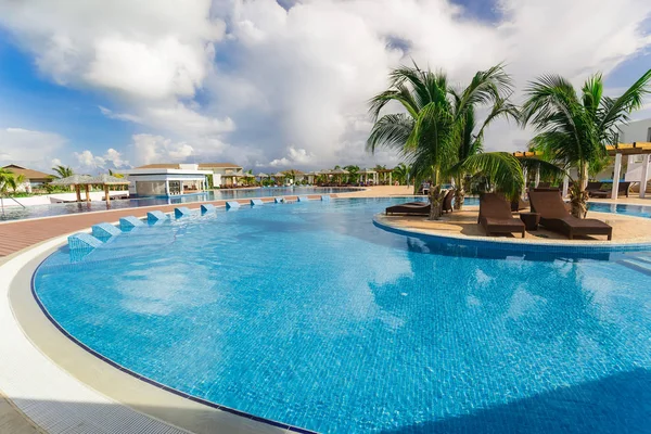 Acogedora vista de una piscina curva cómoda con camas de cerámica sobre fondo azul cielo nublado Fotos de stock