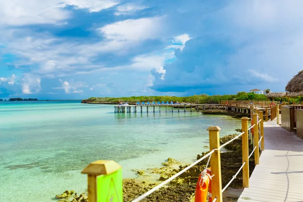 Sakin okyanus ve bulutlu mavi gökyüzü insanlar Küba Cayo Guillermo Adası'nda arka planda rahatlatıcı ile plaj pier güverteden şaşırtıcı manzarasının — Stok fotoğraf
