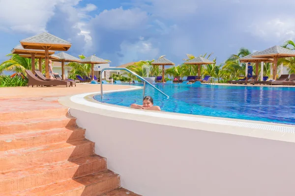 Vista di confortevole piscina accogliente con sorridente bambina rilassante nuoto e godersi la sua vacanza — Foto Stock