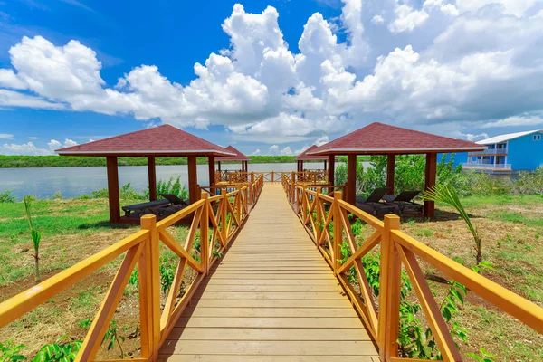 Great amazing view of wooden bridge leading toward beach gazebos in tropical garden park on sunny nice day — Stock Photo, Image