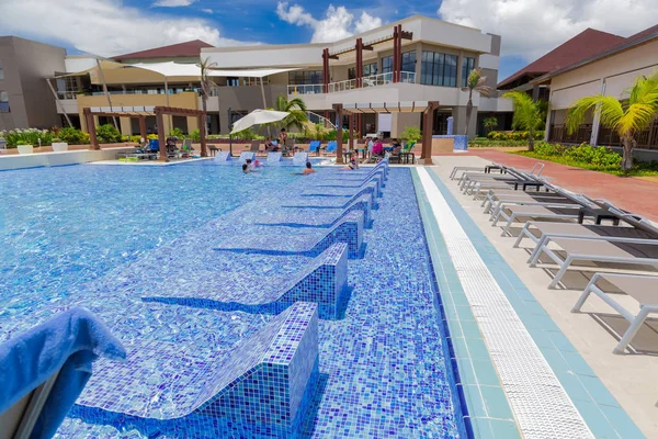 Acogedora vista del complejo piscina al aire libre y jardines del hotel con personas que se relajan en el fondo Imágenes de stock libres de derechos