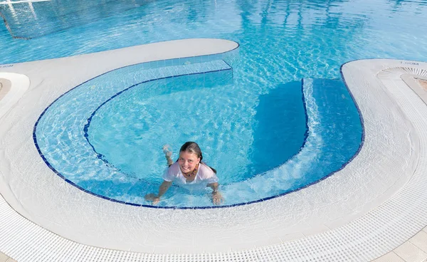 Niña feliz nadando y relajándose en la piscina con agua cristalina en la mañana —  Fotos de Stock