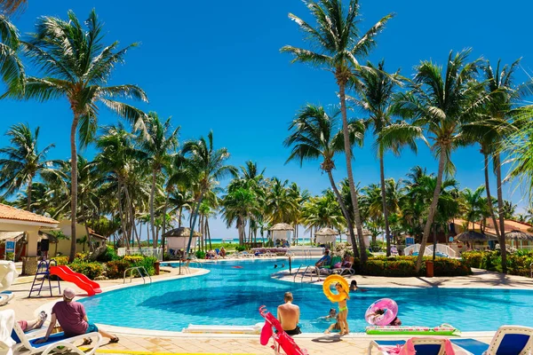 Acogedora piscina jardín tropical con gente y niños disfrutando de su tiempo en un día soleado —  Fotos de Stock