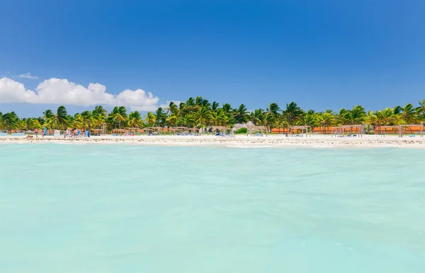 Acogedora vista del jardín tropical, la playa de palmeras y el tranquilo océano turquesa con la gente relajándose, nadando y disfrutando de su tiempo — Foto de Stock