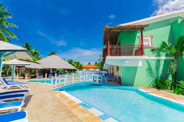 Increíble vista de los jardines del hotel colonial, hermosa piscina acogedora y edificios con estilo retro sobre fondo azul cielo — Foto de Stock