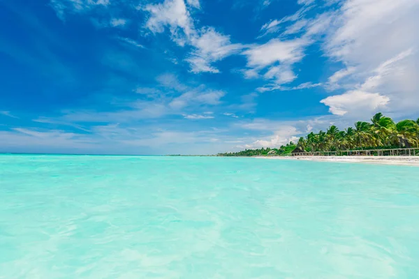 Fascinante vista increíble del fondo del cielo azul profundo y el océano turquesa tranquilo que se fusiona en la línea del horizonte con la playa tropical en el lado — Foto de Stock