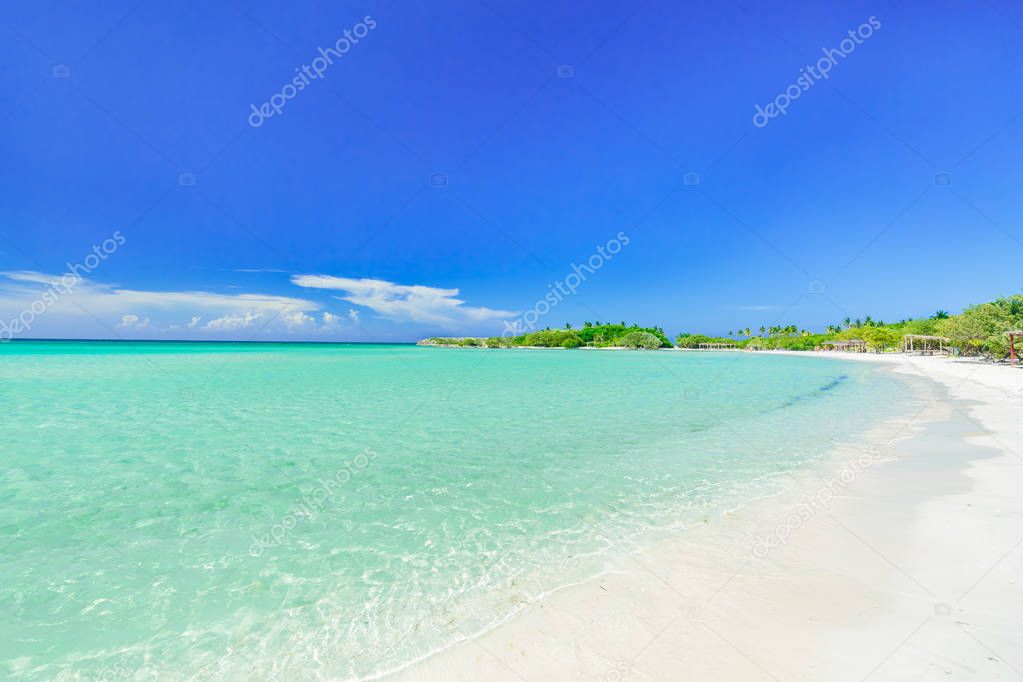 amazing inviting view of tropical white sand beach and tranquil turquoise ocean on blue sky with people in background 