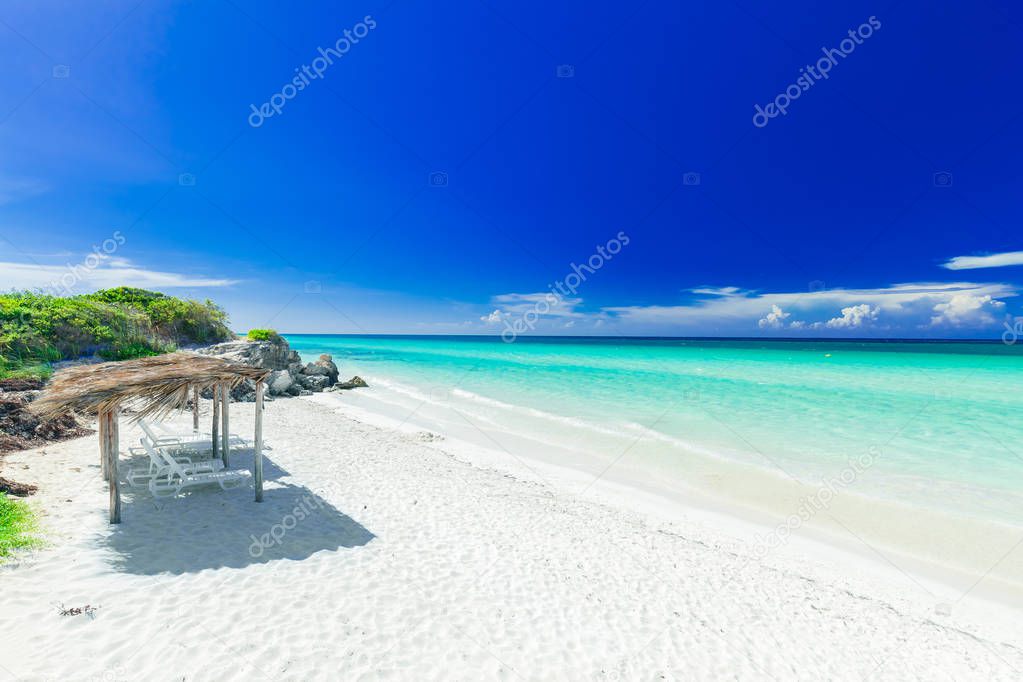amazing inviting view of tropical white sand beach and tranquil turquoise ocean on dark deep, blue sky background 
