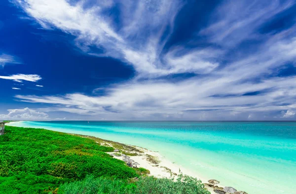 Vue imprenable sur la plage de sable blanc tropical et l'océan tendre turquoise tranquille par une journée d'été ensoleillée et une magie bleue profonde, fond de ciel bleu — Photo