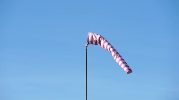 红色和白色条纹的风衣显示了风向和风速方向 锥形风向指示器在蓝天背景下发展 短袜是用织物做成的短锥形的 — 图库视频影像