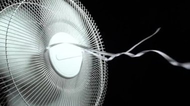 Evin pervanelerinin dönen pervaneleri koyu arka planda. Hava soğutma için elektrikli yer vantilatörü