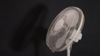 Ev pervanesi yavaşlar ve durur. Havayı serin tutmak için yelpaze hareket ediyor. Koyu arkaplanda video