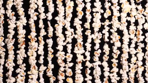 Garlands of popcorn. Background from popcorn for sports and movie news. Popcorn vertically hanging on black background. 4K video — Stock Video