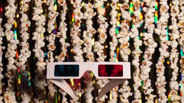 Oskärpa dynamisk bakgrund av kransar från popcorn och gyllene glittrande tinsel. Garlands av popcorn för sport och film nyheter. I förgrunden 3D-glasögon, anaglyf. 4K-video — Stockvideo