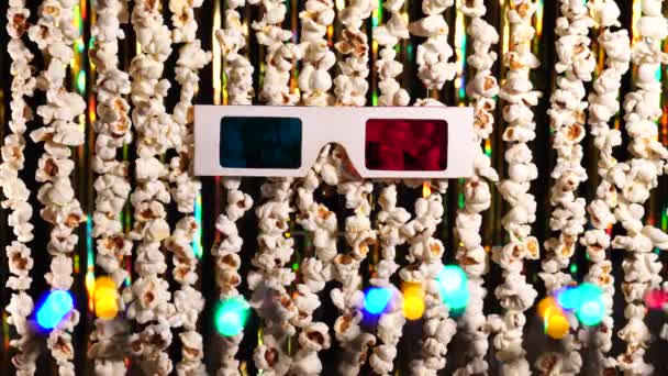 3D gözlükler, yanıp sönen çelenk ışıkları ve bir sürü kızarmış patlamış mısır. Sinema haberleri için patlamış mısırın arka planı. Komik haber, komik eğlence, eğlence. 4K video — Stok video
