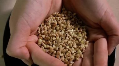 The girl pours the buckwheat out of her hands onto a plate