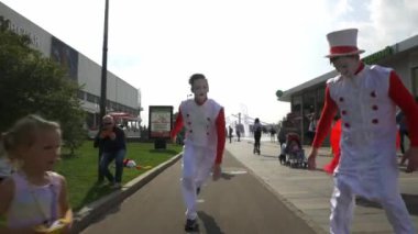 A man in a white suit jumps a somersault
