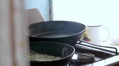 Büyükanne eski bir tavada krep pişirir.