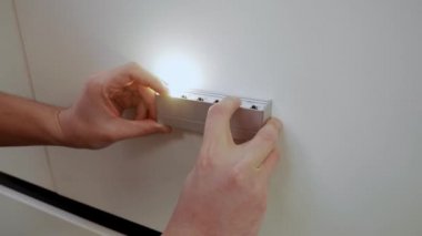 Bir adam duvarda farklı ışıklar dener.
