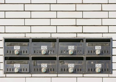 Yıpranmış Japon Çelik Posta Kutusu beyaz tuğla duvar zemininde.