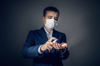 Tıbbi maskeli bir adam ellerini antiseptikle dezenfekte ediyor. Koronavirüs enfeksiyonu kapma riski