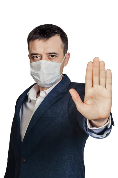 Opriți răspândirea virusului. Un bărbat cu o mască medicală arată un gest de oprire, ținându-și mâna în fața lui, izolat pe un fundal alb — Fotografie, imagine de stoc